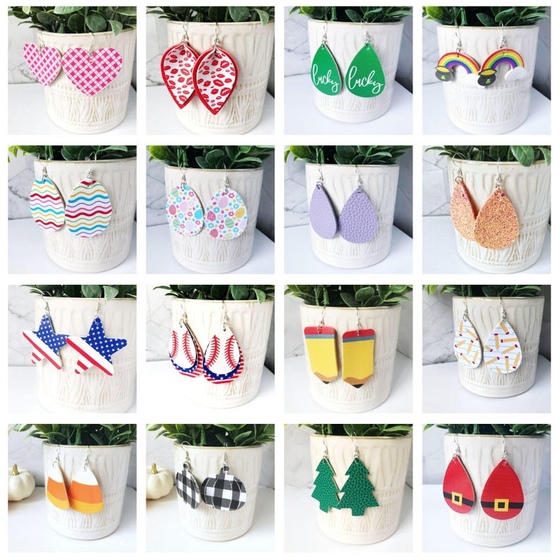 K&ouml;nnte beinhalten: Eine Sammlung verschiedener Ohrringe, die in einem wei&szlig;en Topf ausgestellt sind. Die Ohrringe weisen verschiedene Designs auf, darunter Herzen, Lippen, Kleebl&auml;tter mit dem Text "lucky", Regenbogen, Ostereier, Sterne, Baseb&auml;lle, Bleistifte und Formen mit Feiertagsmotiven.