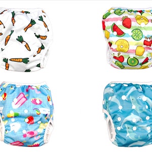 May include: Four different styles of reusable swim diapers for babies and toddlers. The diapers feature various colorful prints, including carrots, fruit, ice cream, and dolphins.