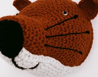 May include: A crocheted fox head wall hanging with brown fur, white teeth, and black eyes and whiskers.
