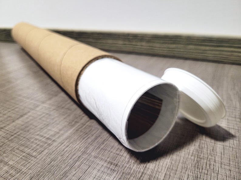 K&ouml;nnte beinhalten: Eine braune Pappr&ouml;hre mit einer wei&szlig;en Papierauskleidung und einem wei&szlig;en Plastikdeckel. Die R&ouml;hre ist teilweise ge&ouml;ffnet und zeigt die wei&szlig;e Papierauskleidung.