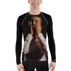 May include: A black long-sleeved shirt with a graphic print of a young boy covering his face with his hands. The boy is wearing a white shirt and is looking distressed.