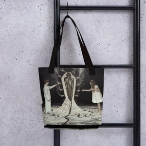 May include: A black tote bag with a design of two children standing on either side of a figure made of sand. The figure is surrounded by small, white objects that resemble cups. The text "Paula Rego" is printed at the bottom of the bag.