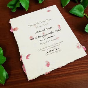 May include: A stack of off-white handmade Lokta printer paper with deckle edges and embedded pink bougainvillea petals. The text reads: Handmade Printer Paper (Deckle Edge), Natural Lokta With Bougainvillea Petal, 8 1/2 x 11 Inches, Pack of 25 sheets.
