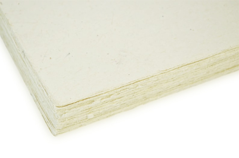 Puede incluir: Primer plano de una pila de hojas de papel de color blanquecino. El papel tiene una textura ligeramente rugosa y est&aacute; hecho de materiales reciclados.