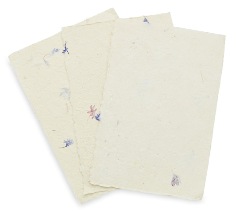 May include: Three rectangular sheets of off-white handmade paper with deckled edges. The paper has a textured, fibrous surface embedded with small, scattered dried flower petals in shades of blue, purple, and pink, creating a natural appearance.