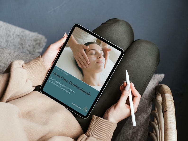 May include: A tablet displaying a skincare guide titled "Skin Care Professionals." The image on the tablet shows a person receiving a facial treatment. A white stylus is held in the hand. The person is sitting on a chair.