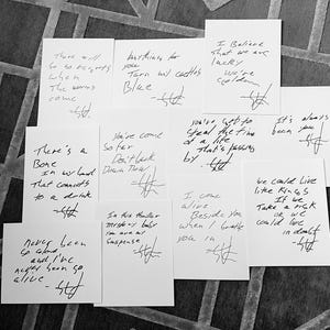 May include: A collection of handwritten notes on white cards with black ink. The notes contain lyrics and song titles. The notes are signed with the initials "STt".