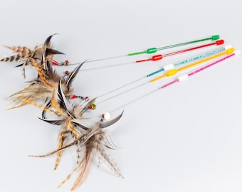 May include: Four cat wand toys featuring long, thin, glittery handles in green, red, blue, and pink. Each wand has a flexible wire attachment ending in a cluster of natural brown, tan, and black striped feathers accented with small, colorful beads.
