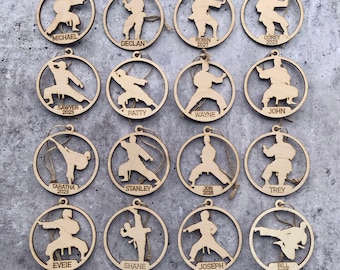 May include: Fifteen round wooden ornaments with a silhouette of a person in a karate pose. Each ornament has a name and year printed on it.