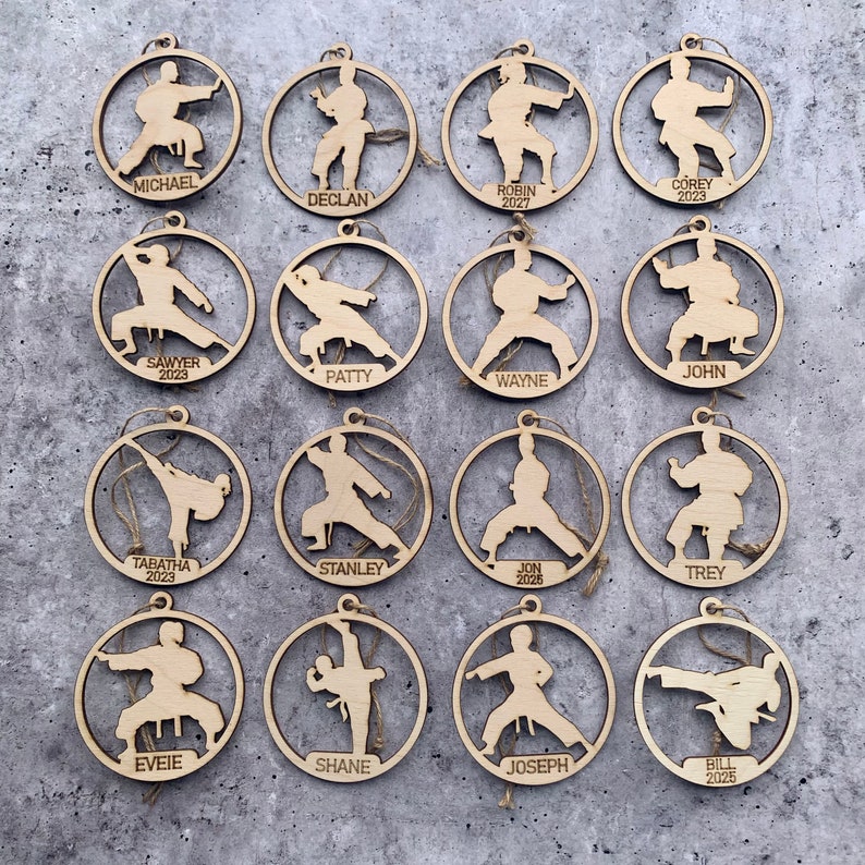 May include: Fifteen round wooden ornaments featuring a silhouette of a person in a karate pose. Each ornament is personalised with a name and year.