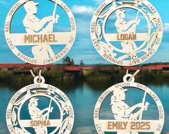 May include: Four wooden ornaments shaped like a circle with a fishing scene inside. Each ornament has a different name on it: Michael, Logan, Sophia, and Emily 2025. The ornaments are decorated with fishing lures and the words "reel", "cast", "swivel", "spoon", "bait", "lake", "hook", "jig", "crank", and "spinner".