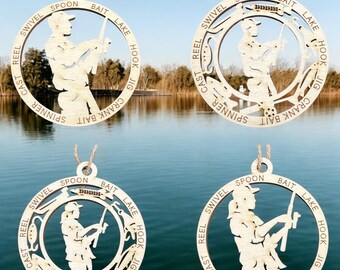 May include: Four wooden ornaments shaped like circles with a silhouette of a person fishing inside. Each ornament has the words "CAST REEL SWIVEL SPOON BAIT LAKE HOOK JIG CRANK BAIT SPINNER" written around the edge.