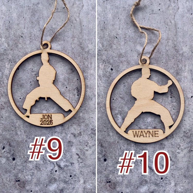 May include: Two wooden ornaments shaped like a karate person with a name and year engraved on each. The ornament on the left says "JON 2025" and the ornament on the right says "WAYNE".