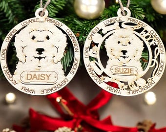 May include: Two wooden Christmas ornaments shaped like dog heads with the words "Woof", "Loyal", "Caring", "Lovable", "Friendly", "Companion", "Joyous", "Dependable", "Warm", "Adorable" around the edges. The ornaments have the names "Daisy" and "Suzie" on them.