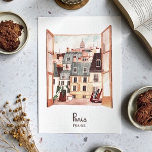 Peut inclure: Peinture à l'aquarelle d'une vue de fenêtre sur les toits parisiens avec une plante verte dans un pot en terre cuite. Le texte "Paris, FRANCE" est écrit sous la fenêtre.