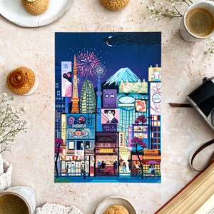 May include: A vibrant illustration of a Japanese cityscape at night, with landmarks, fireworks, and street scenes. The artwork is surrounded by pastries, coffee, a camera, and a book.