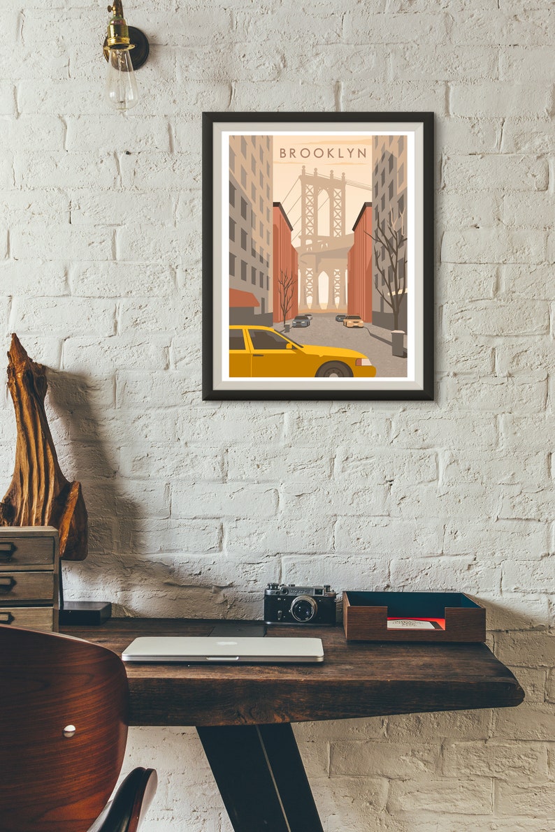 May include: A framed print of a stylized illustration of a yellow taxi cab driving down a street in Brooklyn, New York. The Brooklyn Bridge is visible in the background. The print has the word "BROOKLYN" in the top center.