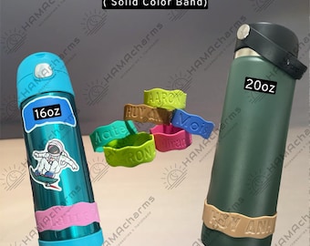 May include: Customized engraved silicone water bottle labels in solid colors, shown on a 16oz teal bottle with an astronaut sticker and a 20oz dark green bottle. The bands feature embossed names including Aaron, Huy, Mois, and others.