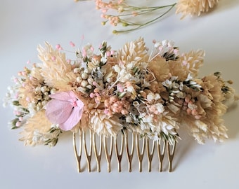 May include: A gold hair comb adorned with dried flowers in shades of cream, white, and pink. The comb features a single pink flower in the center and is perfect for adding a touch of rustic elegance to any hairstyle.