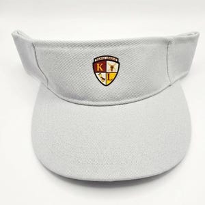 May include: A light gray visor featuring a centered shield-shaped emblem. The emblem displays the text KAPPA LEAGUE at the top, with the letter K in a maroon section and the letter L in a yellow section, alongside a small graphic of a scroll.