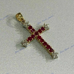 May include: A gold cross pendant with red and white gemstones. The cross is set with small, round red gemstones and smaller, round white gemstones.