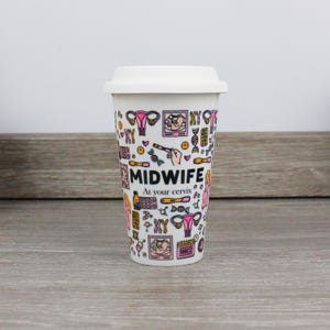 May include: White travel mug with a pink and black design featuring the word "MIDWIFE" and the phrase "At your cervix". The mug is covered in illustrations of medical symbols, including a uterus, a fetus, and a DNA strand.