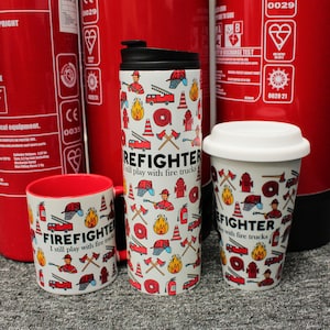 Könnte beinhalten: Drei weiße Tassen mit Feuerwehr-Motiv. Die Tassen haben einen weißen Hintergrund mit roten, gelben und schwarzen Feuerwehr-Symbolen und dem Text "FIREFIGHTER I still play with fire trucks".