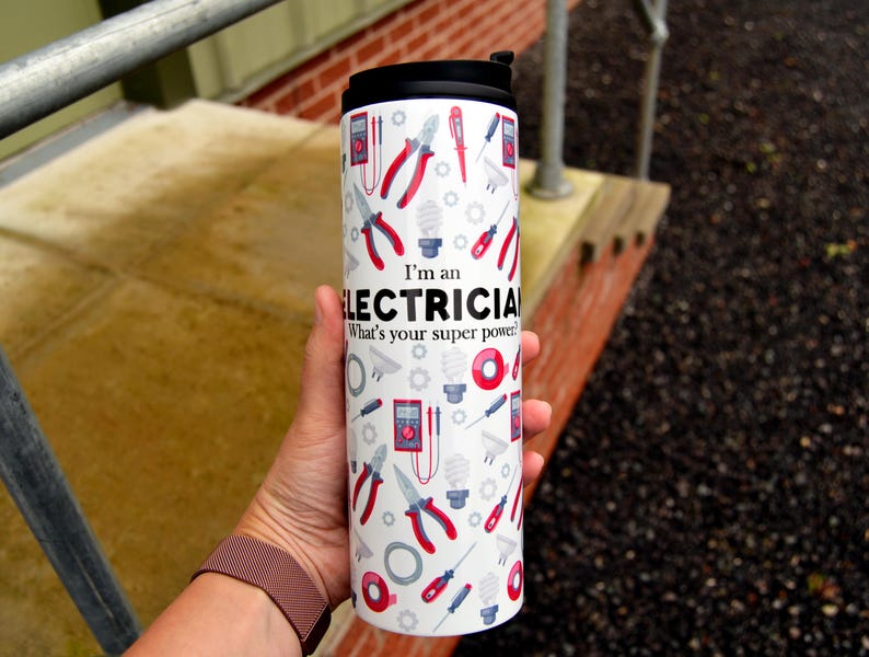 May include: White travel mug with a black lid and a design of electrical tools and the text "I'm an Electrician. What's your superpower?"