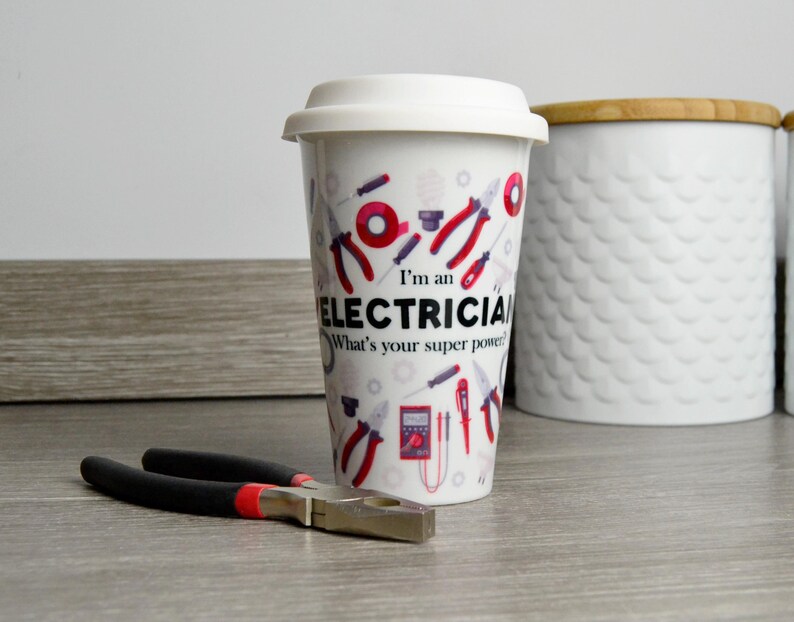 May include: White ceramic travel mug with a red, black, and gray design of electrical tools and the text "I'm an Electrician. What's your super power?"
