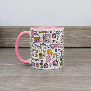 May include: A white ceramic mug with a pink rim and handle. The mug is decorated with a colorful pattern of illustrations related to pregnancy, including a calendar, a sonogram, a uterus, a DNA strand, and a pregnant woman.