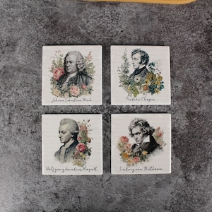 Op de afbeelding: Set van vier vierkante onderzetters met portretten van beroemde componisten: Johann Sebastian Bach, Frédéric Chopin, Wolfgang Amadeus Mozart en Ludwig van Beethoven. Elke onderzetter heeft een bloemenontwerp en de naam van de componist.