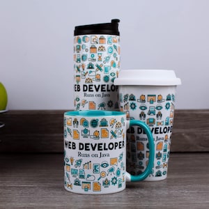 Op de afbeelding: Drie witte keramische mokken en een reisbeker met een turquoise binnenkant en handvat. De mokken en de beker zijn versierd met een patroon van tech-iconen en de tekst "WEB DEVELOPER Runs on Java."