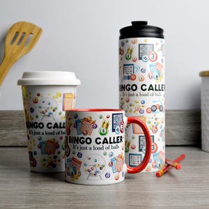 Könnte beinhalten: Drei weiße Tassen mit rotem Rand und einem schwarz-weißen Design aus Bingokugeln und Karten. Der Text auf den Tassen lautet "Bingo Caller It's just a load of balls".