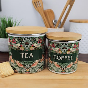 May include: Two ceramic canisters with green and white floral designs and bamboo lids. The canisters are labelled "TEA" and "COFFEE".
