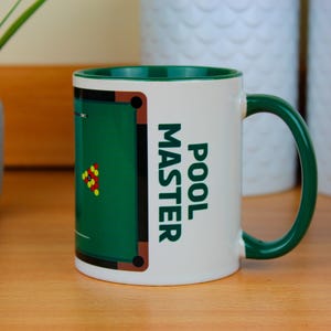 May include: White ceramic mug with a green rim and handle. The mug features a green pool table design with the text "POOL MASTER" printed on the side.