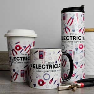 May include: Three mugs with a white background and black handles. The mugs have a pattern of electrical tools and the text "I'm an Electrician. What's your super power?"  The mugs are on a gray surface with a pair of pliers.