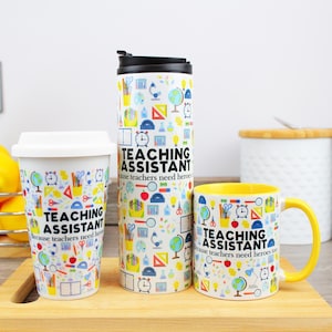Può includere: Tre tazze bianche con un bordo giallo. Le tazze hanno un motivo colorato di forniture scolastiche e il testo "Assistente di insegnamento Perché gli insegnanti hanno bisogno anche di eroi".
