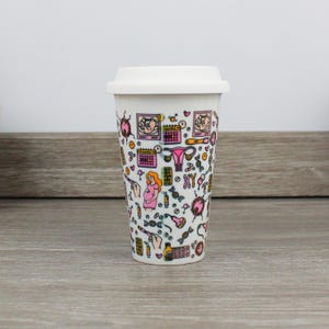 May include: White travel mug with a pink and black design featuring illustrations of pregnancy, fertility, and motherhood. The design includes images of a uterus, a calendar, a baby, and a DNA strand.
