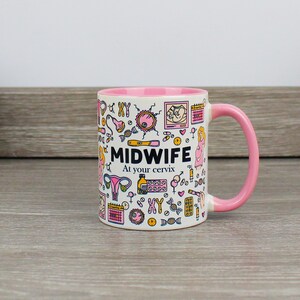 May include: A pink and white ceramic mug with a pink handle. The mug has a design of various medical illustrations related to pregnancy and childbirth. The text "MIDWIFE At your cervix" is printed on the mug.