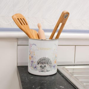Peut inclure: Ensemble de trois mugs en céramique avec un glaçage moucheté de couleur crème. Chaque mug présente un motif peint à la main différent : une feuille bleue et verte, une fleur jaune et une baie rouge. Les mugs ont un design simple et moderne.