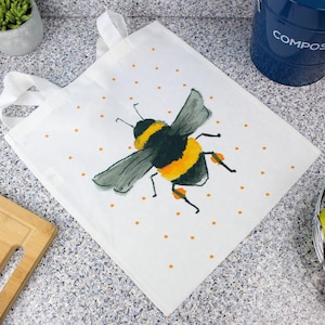Può includere: Borsa tote bianca con un'illustrazione di un'ape in nero, giallo e grigio. La borsa ha manici bianchi e piccoli pois arancioni. Una borsa riutilizzabile per la spesa, perfetta per trasportare generi alimentari o altri oggetti.