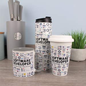 Può includere: Un set di tazze bianche e un bicchiere da viaggio, decorati con un motivo di icone di computer e la scritta "SOFTWARE DEVELOPER: Beverage Not Found". Le tazze hanno manici e interni grigi.