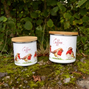 Peut inclure: Deux boîtes en céramique blanche avec couvercles en bambou, ornées d'un motif aquarelle de rouges-gorges et du mot "Coffee".