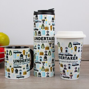 Puede incluir: Tres tazas con un diseño en blanco y negro que presenta una variedad de iconos relacionados con el funeral, incluyendo un coche fúnebre, una lápida y una cruz. El texto en las tazas dice "Undertaker, Not your typical dead-end job".