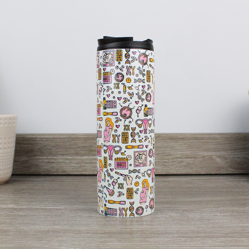 May include: White travel mug with a black lid and a pattern of pink and yellow illustrations related to pregnancy, including a pregnant woman, a uterus, a baby, and a calendar. The text "XY" is repeated throughout the pattern.