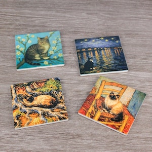Può includere: Set di quattro sottobicchieri quadrati in ceramica con opere d'arte a tema gatto. Ogni sottobicchiere presenta un'immagine diversa di un gatto, tra cui un tabby su un ramo, un gatto bianco e nero sull'acqua e due ritratti di gatti.