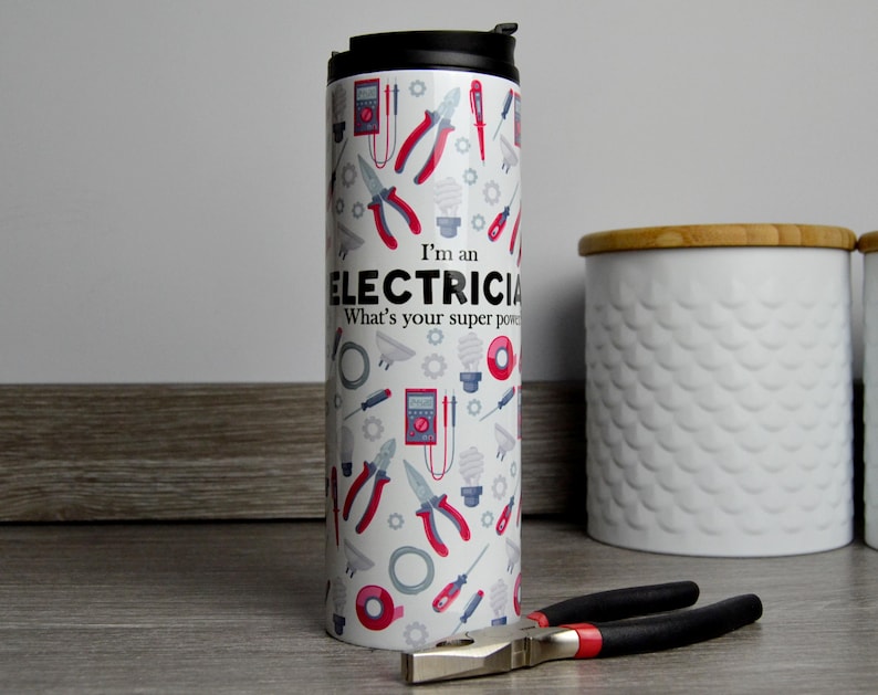 May include: White travel mug with a red and black design of electrician tools and the text "I'm an Electrician. What's your superpower?"