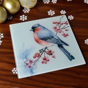 Puede incluir: Un pájaro azul y rojo con el pecho blanco se posa en una rama con bayas rojas. El fondo es una acuarela de color azul claro.