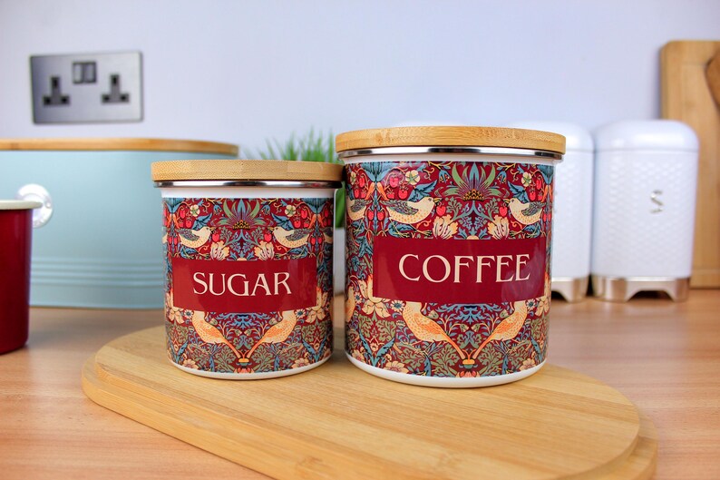 May include: Two ceramic canisters with bamboo lids, one labeled "Sugar" and the other "Coffee". Both canisters feature a colorful floral and bird pattern.