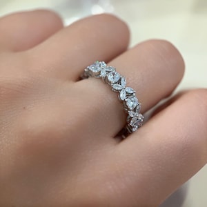 Può includere: Un anello a fascia d'argento con un delicato design floreale con piccole pietre preziose trasparenti.